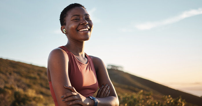 Woman smiling outside wearing athletic clothes.